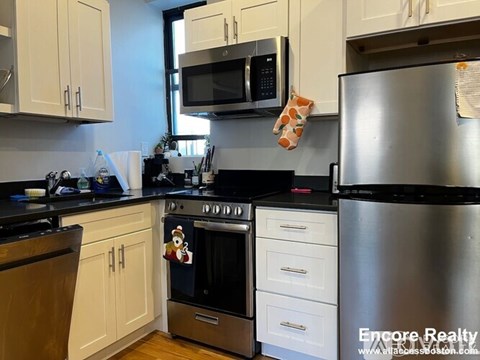 A kitchen with a stainless steel refrigerator, oven, and microwave.