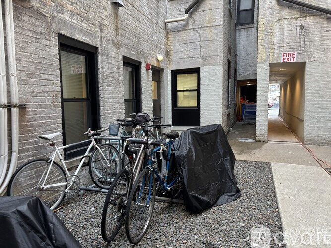 A bicycle is parked in front of a building with a fire exit sign.