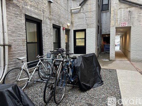 A bicycle is parked in front of a building with a fire exit sign.