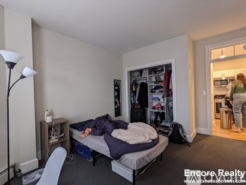 A bedroom with a bed, a chair, and a wardrobe.