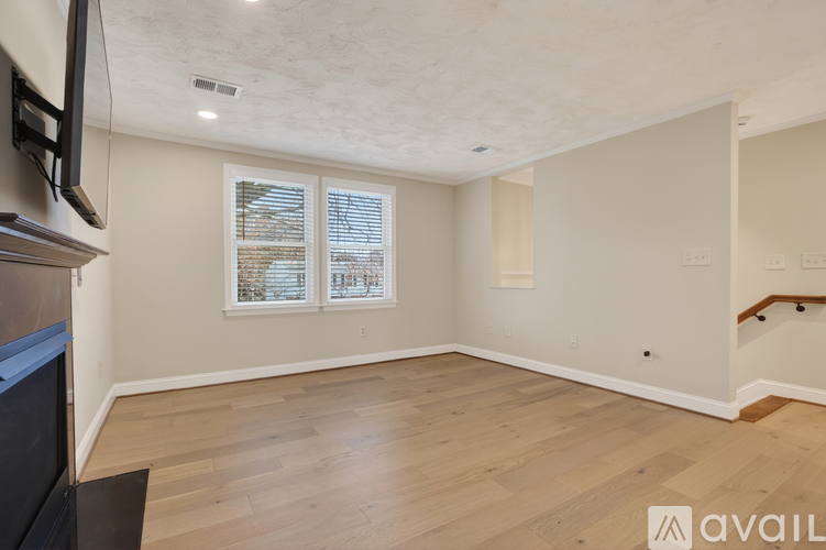 A spacious living room with wooden flooring and a television on the left side.