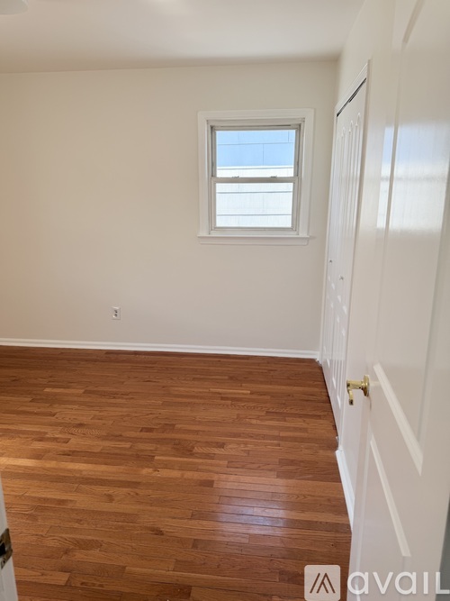A room with wooden flooring and a window.