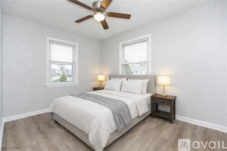 A bedroom with a bed, two lamps, and a ceiling fan.