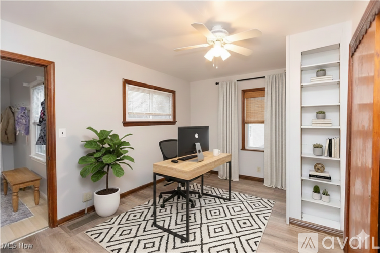 A room with a desk, chair, and a potted plant.