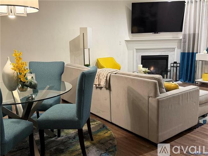 A living room with a fireplace, a couch, a chair, and a glass table.