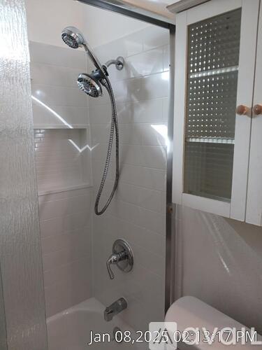 A white shower with a glass door and a shower head.
