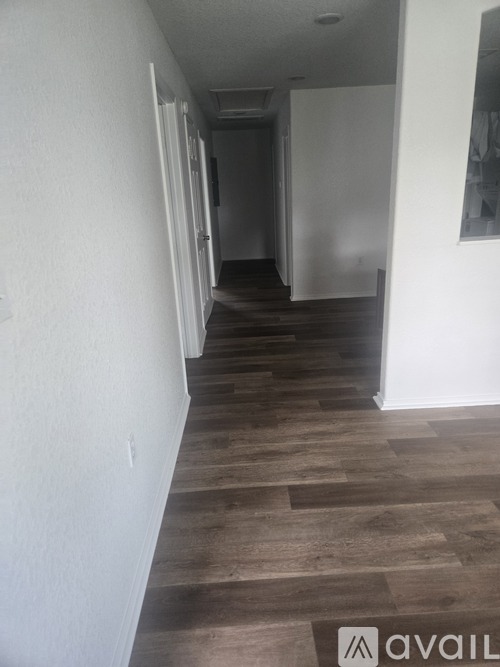 A hallway with wood flooring and white walls.