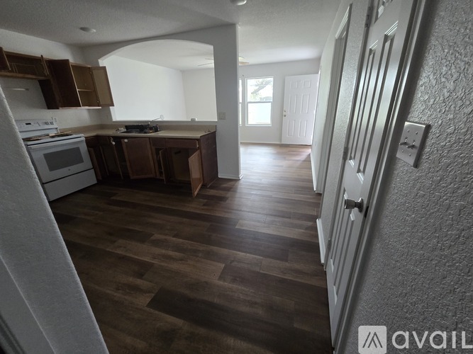 A kitchen with wooden floors and a white wall.