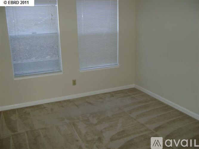 A room with a tiled floor and two windows with blinds.
