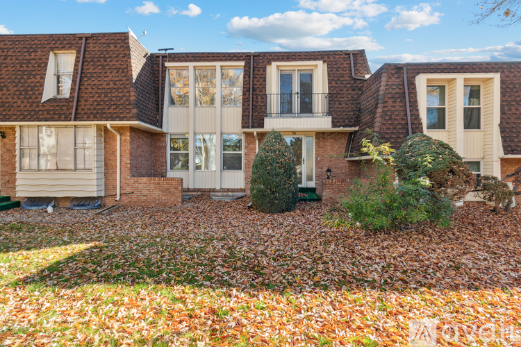 A house with a brick facade and a large front yard covered in leaves.