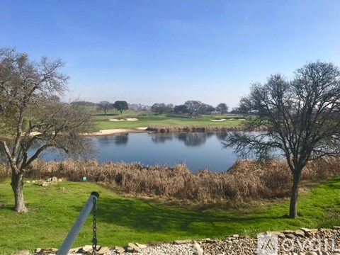 A serene landscape with a lake, trees, and a stone wall.