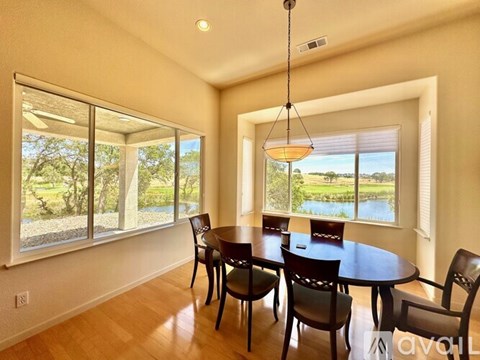 A dining room with a table and chairs and a view of the outdoors.