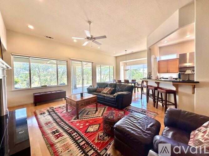 A living room with a rug and a fan.