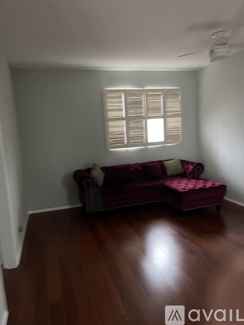 A room with a red couch and wooden floors.