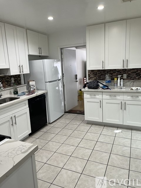 A kitchen with white cabinets and a white refrigerator.