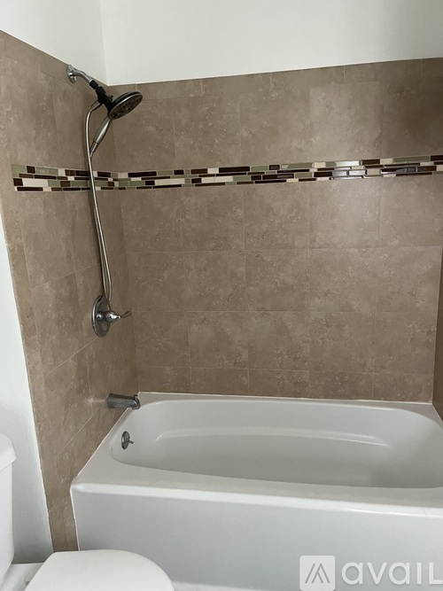 A bathroom with a white bathtub and a shower head.