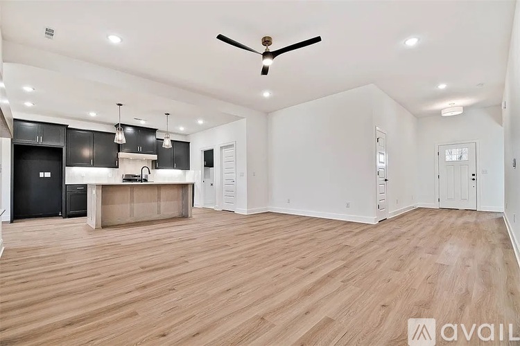 A spacious room with wooden flooring and a ceiling fan.