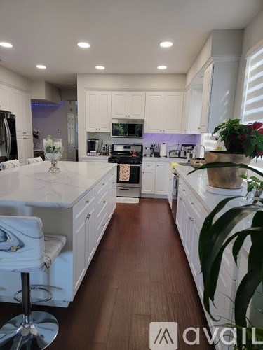 A modern kitchen with white cabinets and a wooden floor.