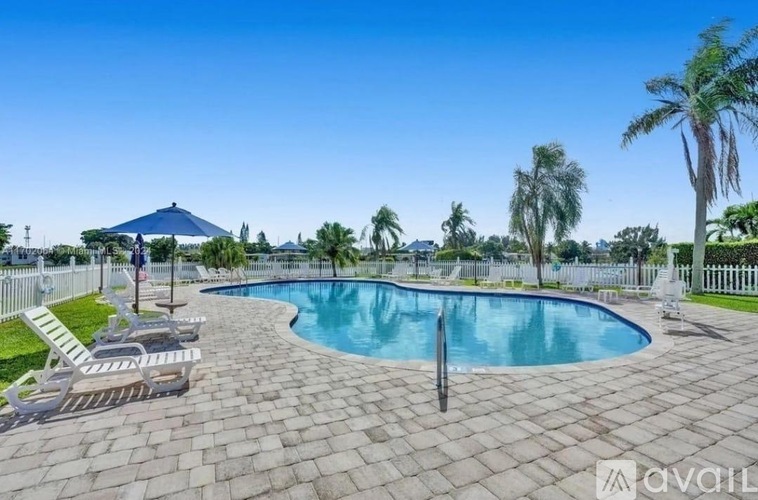 A swimming pool surrounded by palm trees and a fence.