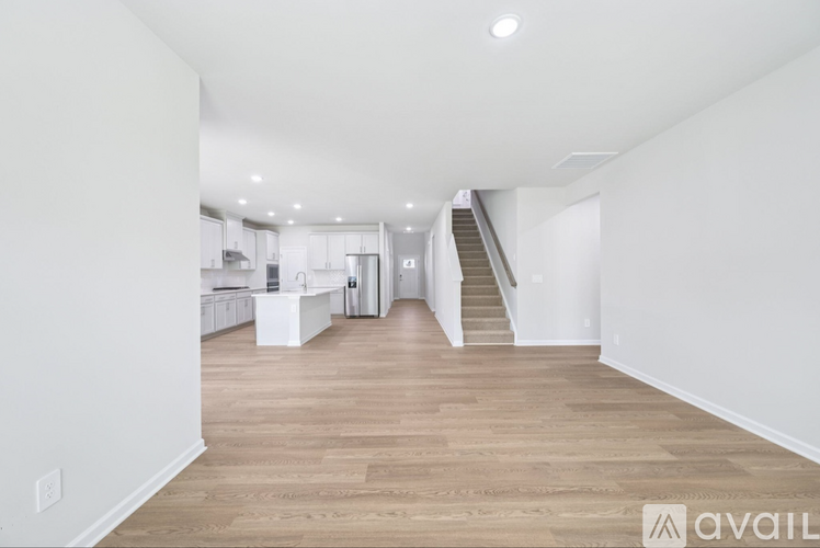 A spacious living room with wooden flooring and a staircase leading to another room.