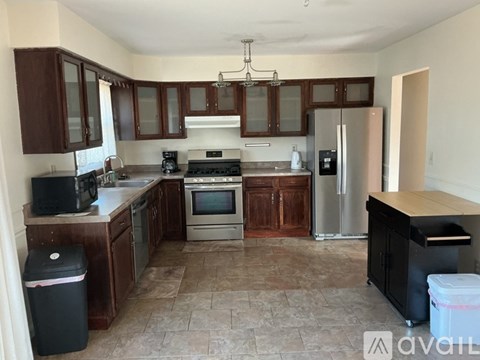 A kitchen with brown cabinets and a black fridge.