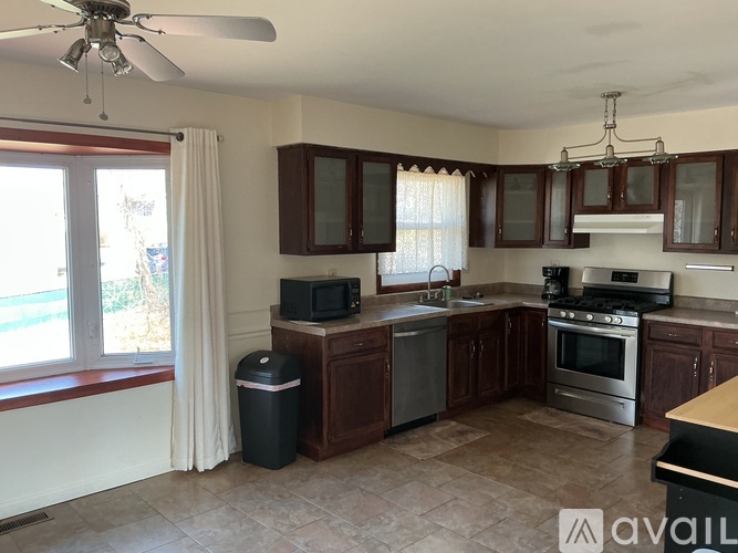 A kitchen with brown cabinets and a black trash can.