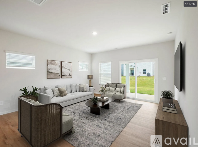 A modern living room with a large sofa, a coffee table, and a flat-screen TV mounted on the wall.