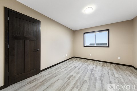 A room with a wooden floor and a window with a view of a building outside.