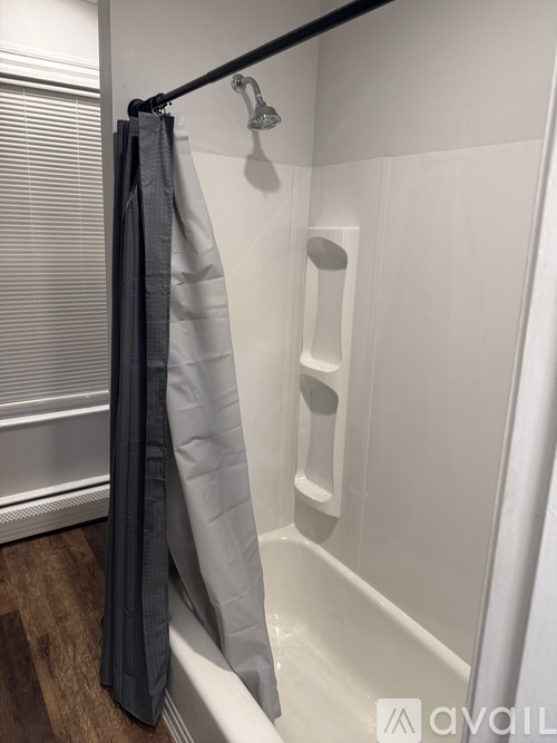 A white bathroom with a grey shower curtain.