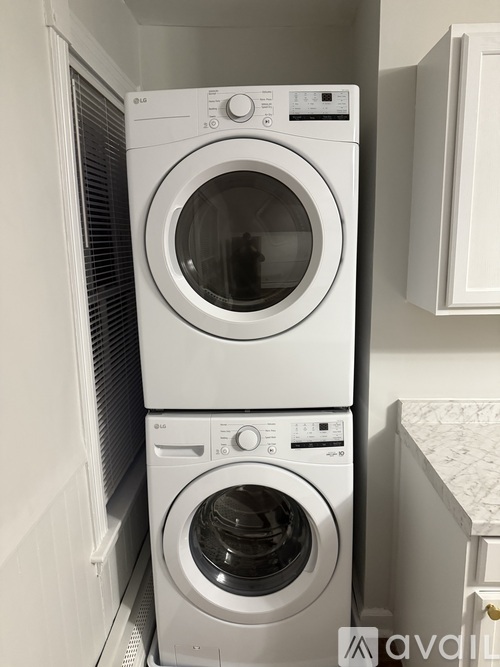 Two white LG front loading washing machines stacked on top of each other.