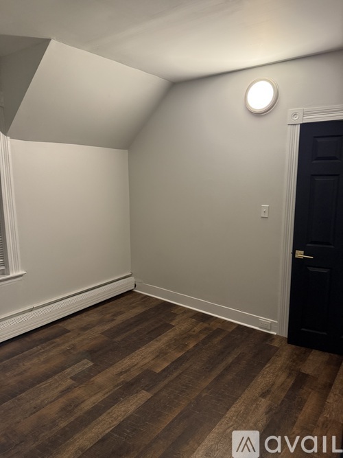 A room with a wooden floor and a black door.