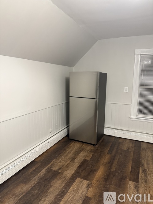 A kitchen with a stainless steel refrigerator and wooden flooring.