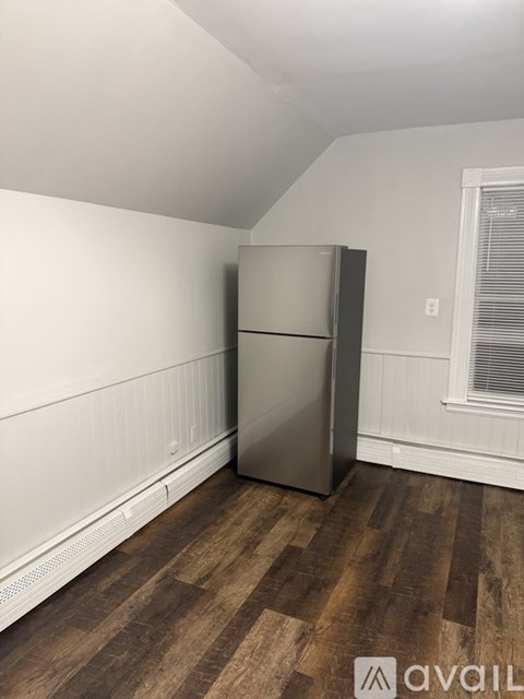 A kitchen with a stainless steel refrigerator and wooden flooring.