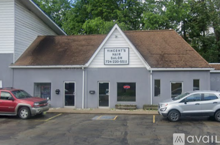 A grey building with a red car parked in front.