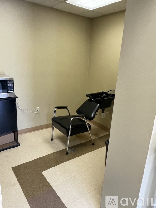 A room with a black chair and a microwave.