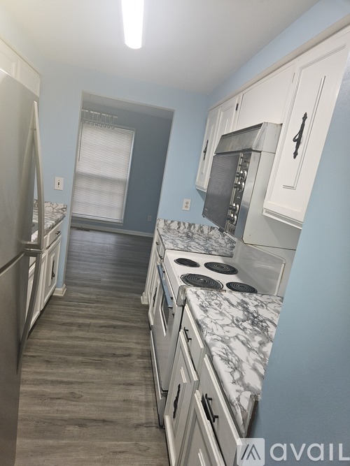 A kitchen with a stove top oven and white cabinets.