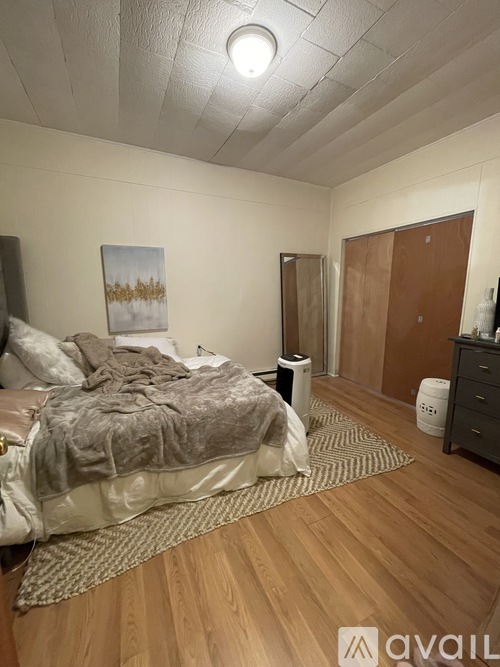 A bedroom with a bed, dresser, and a painting on the wall.