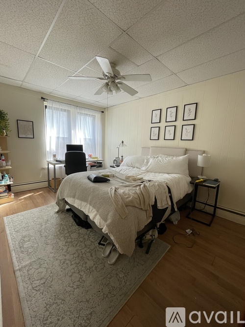 A bedroom with a bed, a ceiling fan, and a window with curtains.