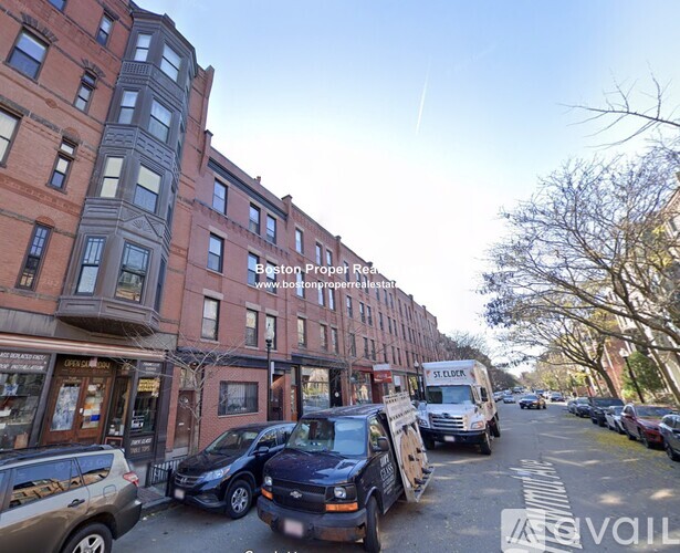 A street view of a residential area with parked cars and buildings.