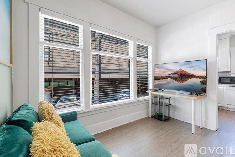 A living room with a couch, a television, and a window with blinds.