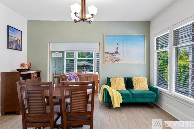 A living room with a green couch and a painting of a lighthouse on the wall.