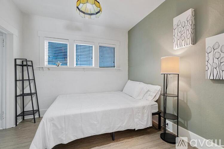A bedroom with a white bed and a lamp on the side table.