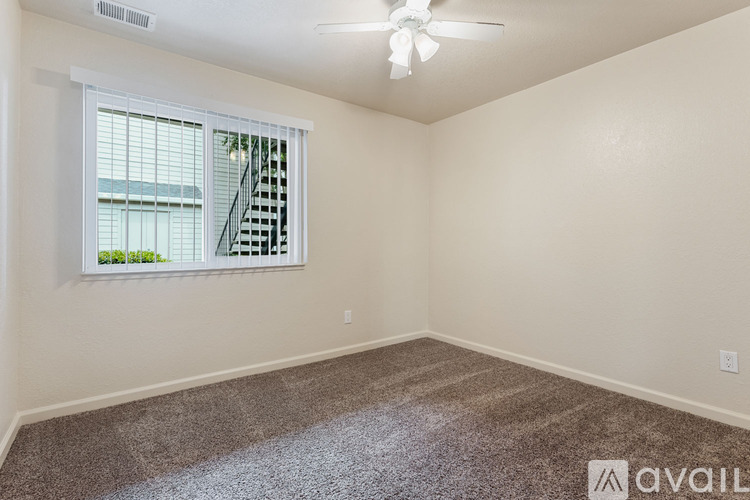 A room with a carpeted floor and a window with a view of a building outside.