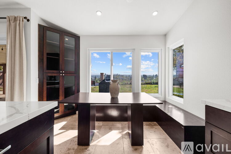A modern kitchen with a table and a view of the outside.