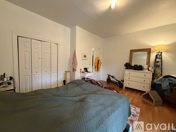 A bedroom with a bed, dresser, mirror, and a flag hanging on the wall.
