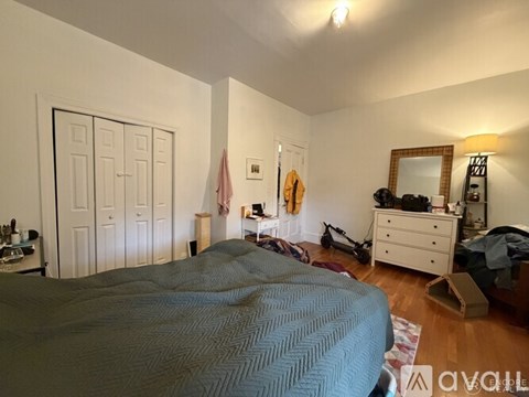 A bedroom with a bed, dresser, mirror, and a flag hanging on the wall.
