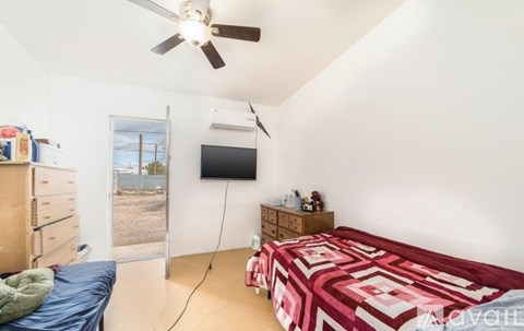 A bedroom with a bed, dresser, and a ceiling fan.
