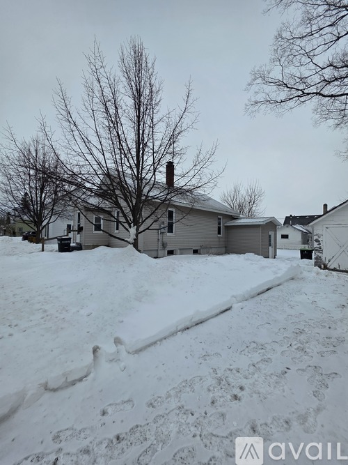 A house with a snow-covered ground and a bare tree in front.