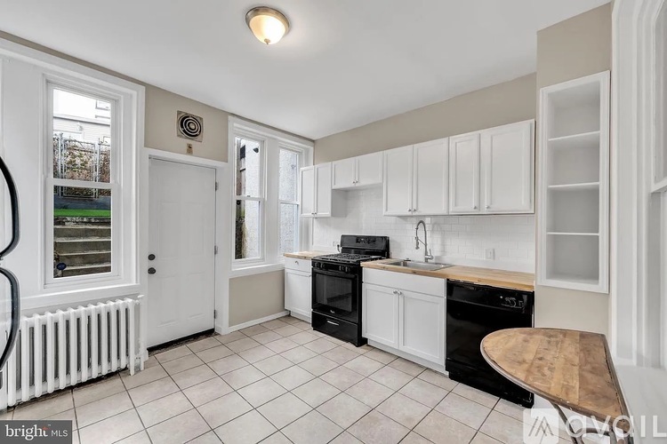 A kitchen with white cabinets and black appliances.