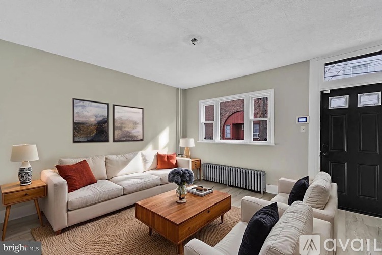 A living room with a white couch, a wooden coffee table, and a painting on the wall.